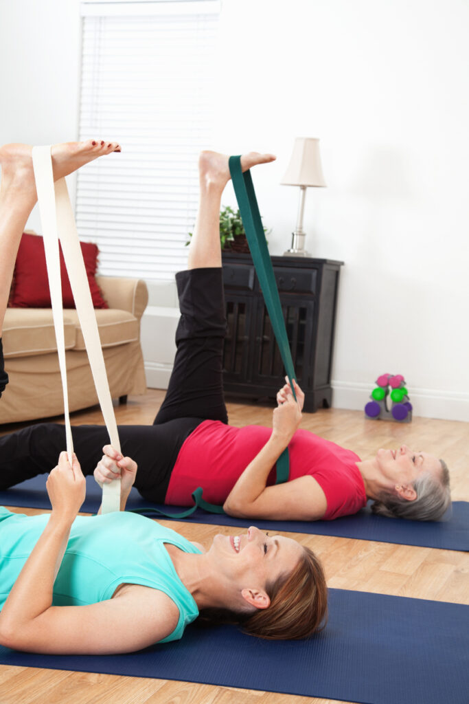 Exercise Partners Doing Yoga Strap Stretching In Living Room